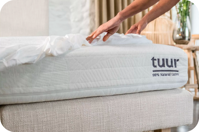 Vrouw die het bed opmaakt met het Tuur hoeslaken